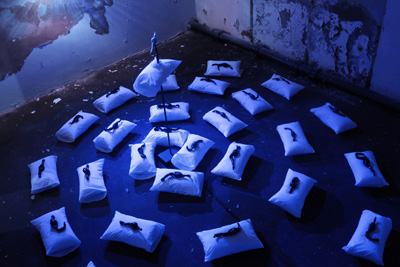 Sam McKee, Thoughts in chase, 2008 – 2009, 28 ceramic pieces on 28 pillows (40x20cm), metal spear (106cm), blue light; photo Joanna Karolini
